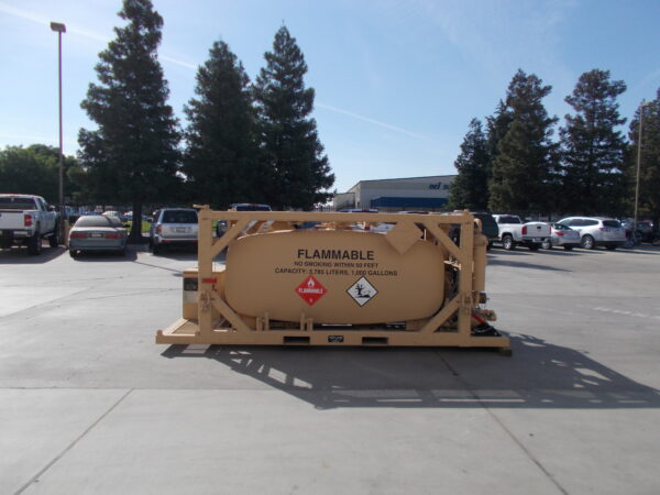Large tan tanker trailer labeled FLAMMABLE in a parking lot with cars and tall trees in the background.